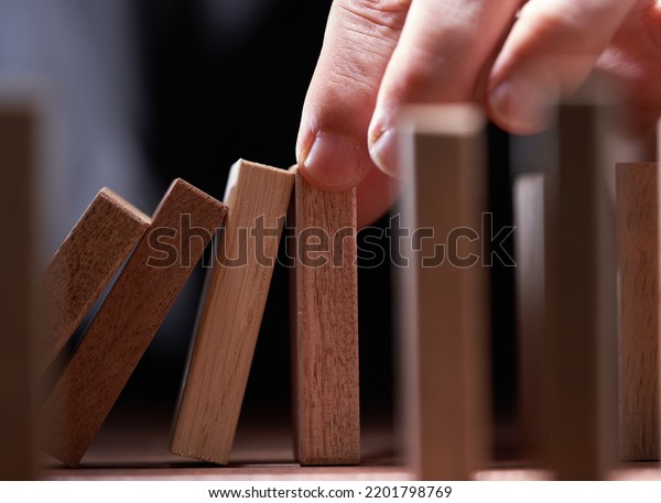 Businessman Stop Domino Effect. Risk\
Management and Insurance Concept                          \
