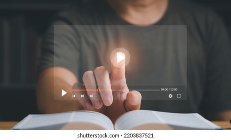 Businessman or student playing the video for learning new technology or music. Finger pointing at play button on virtual screen and a book is on the table. Studying or learning concept. - Shutterstock ID 2203837521