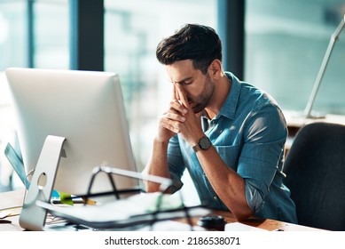 Businessman suffering from a headache or migraine due to stress caused by deadlines and work pressures. Professional in pain feeling anxious, overwhelmed and stressed while busy on his computer desk