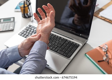 Businessman suffering from wrist pain in office
