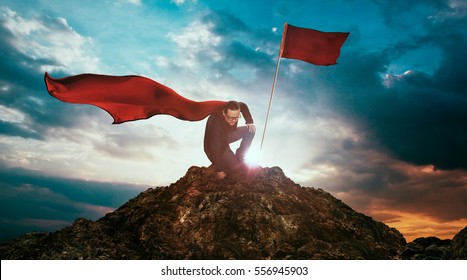 Businessman In A Suit And Cape Hero On Top Of A Mountain,Business Success Concept.