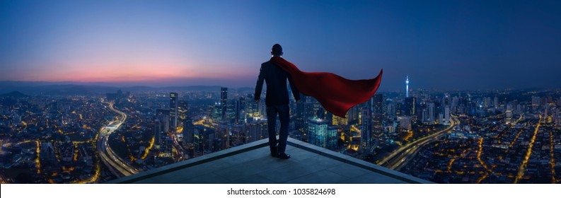 Businessman in suit and cape hero stand at rooftop looking great cityscape view and thinking business plan of the future . Night scene .