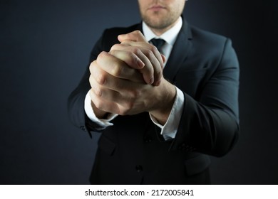 A Businessman In A Suit Expresses A Gesture Of Support With Two Hands Folded Together.