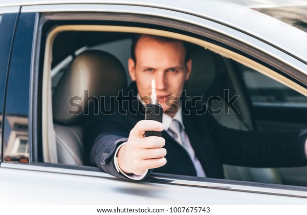 Businessman in a suit giving a car\
keys.dealership and rental\
concept