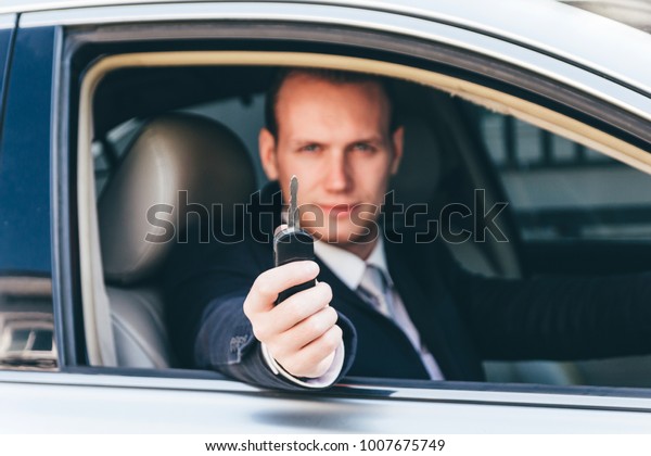 Businessman in a suit giving a car\
keys.dealership and rental\
concept