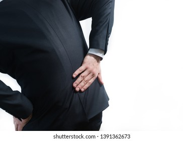 Businessman in a suit having a backache. Bending over in pain with hands holding lower back