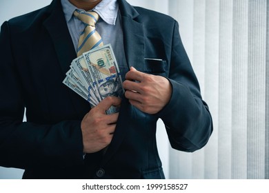 businessman in a suit He was collecting dollar bills in his suit pocket inside his chest. - Shutterstock ID 1999158527
