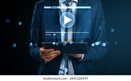 Businessman in suit holding a tablet with a floating video player interface, glowing light elements around, on dark background, concept of streaming