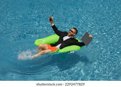 Businessman in suit with laptop in swimming pool. Crazy business man on summer vacation. Excited businessman in wet suit in swim pool. Funny business man, crazy comic business concept. Remote working.