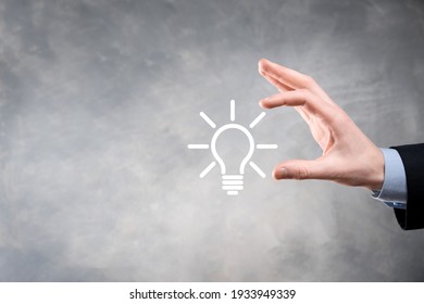 Businessman in a suit with a light bulb in his hands. Holds a glowing idea icon in his hand. With a place for text.
