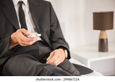 Businessman In Suit Lying On Bed And Watching TV At The Hotel Room. Close-up.