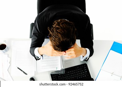 Businessman in suit puts his face in his hands when he is overwhelmed with too much work