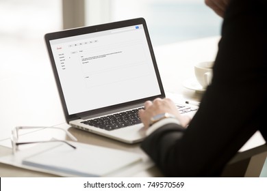 Businessman In Suit Reading Short Corporate Email On Laptop Screen. CEO Browsing Message About Promotion, Highlights Of New Business Deal, Important Reminder. Rear View Over Shoulder, Focus On Screen.