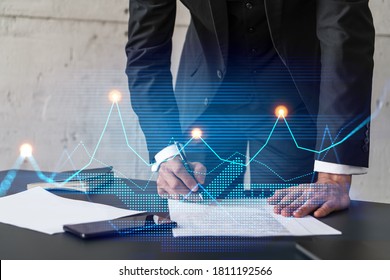 Businessman in suit signs contract. Double exposure with financial chart hologram. Man signing mortgage agreement. Real estate market analysis and investment concept. - Shutterstock ID 1811192566