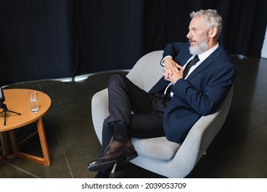 Businessman In Suit Sitting On Armchair During Talk Show