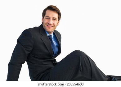 Businessman In Suit Sitting On Floor While Looking At Camera On White Background