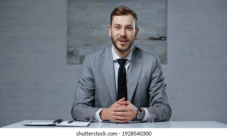 businessman in suit talking while looking at camera during interview in office - Powered by Shutterstock