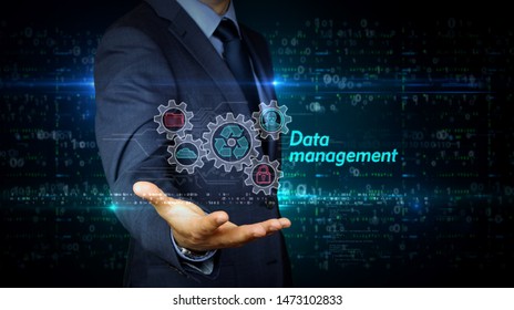 A businessman in a suit touch the screen with data management hologram. Man using hand on virtual display interface. Files storage, cyber security, computer and digital technology futuristic concept. - Shutterstock ID 1473102833