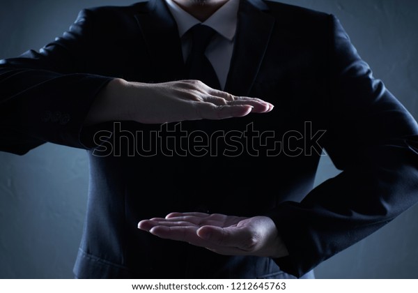 Businessman in suit with two\
hands in position to protect something (focus on hand, blur out the\
suit).