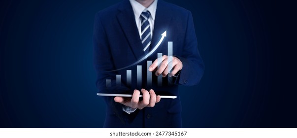 Businessman in a suit using a tablet with a digital bar chart showing growth. Concepts of business, finance, investment, profit, and development in a corporate setting - Powered by Shutterstock