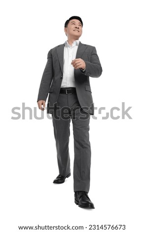 Businessman in suit walking on white background, low angle view