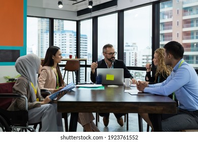 Businessman In Suit And Wearing Glasses Presenting Of His Work To Multicultural Corporate Colleagues At Meeting Room In The Modern Office. Diverse Corporate Colleagues