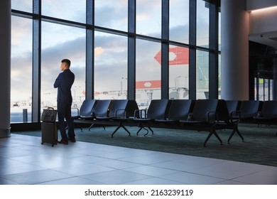Businessman with suitcase and bag in waiting area at airport