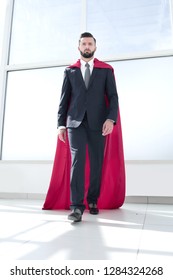 Businessman In A Superman Cloak Standing In A Bright Office