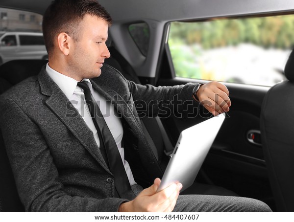 Businessman with tablet in a
car