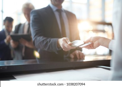 Businessman taking back his passport and ticket from hand of administrator after check-in - Shutterstock ID 1038207094