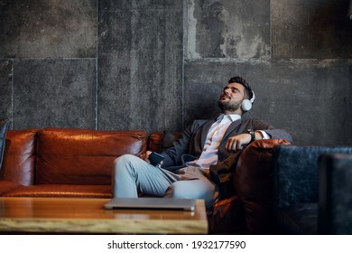 Businessman Taking A Break And Enjoying Music While Sitting On A Couch In The Modern Concept Hotel Lobby. Technology, Free Time, Take Your Time, Rest