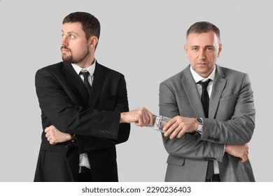 Businessman taking bribe from man on grey background - Shutterstock ID 2290236403