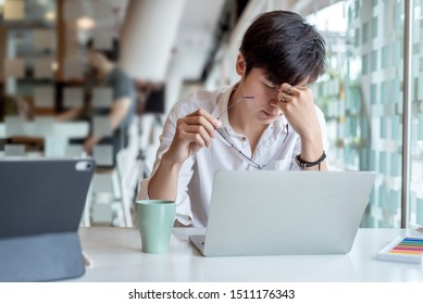 Businessman taking off glasses, feel tired from long hours working on laptop in the office. - Powered by Shutterstock