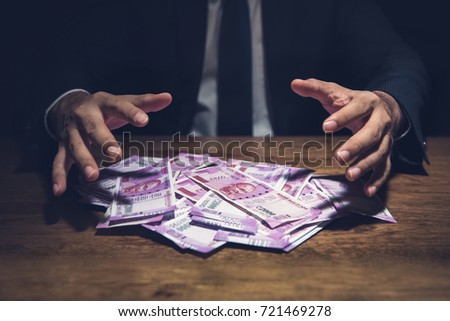 Businessman taking pile of money, Indian Rupee banknotes, on his desk in a dark office  - corruption concept Foto stock © 