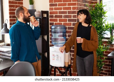 Businessman taking work break talking with executive manager collaborating and communicating in startup office drinking cup of water as refreshment. Businesspeople sitting near to water cooler