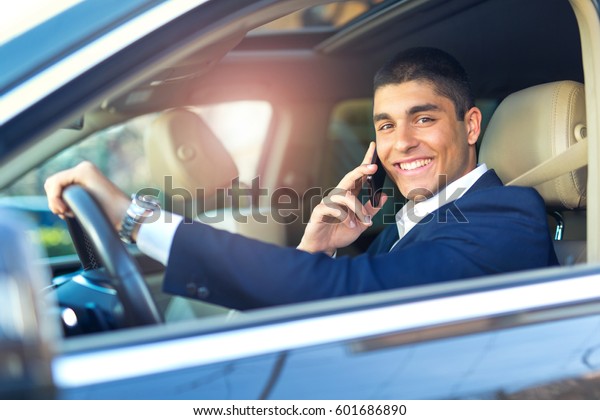 Businessman talk in\
car. Confident businessman talking on the mobile phone and looking\
away while driving his\
car.