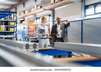 Businessman talking to businesswoman in factory - Powered by Shutterstock