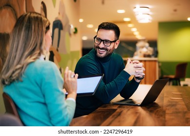 Businessman talking with a female colleague about their accomplishments, sitting at the office. - Shutterstock ID 2247296419