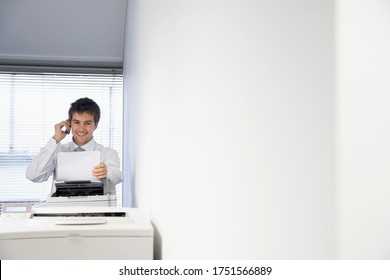 Businessman Talking On Cell Phone And Receiving Fax