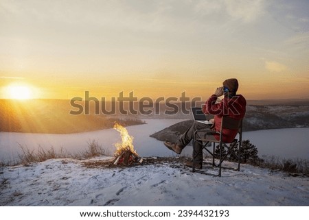 businessman talking on his phone and using a laptop during winter holiday in nature. . freedom, remote work concept.