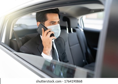 Businessman talking on mobile phone while wearing face mask in taxi during coronavirus crisis - Powered by Shutterstock