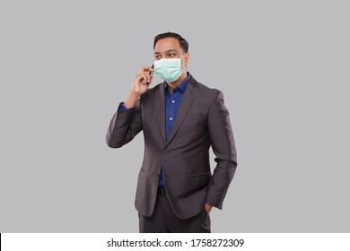 Businessman Talking on Phone Wearing Medical Mask Isolated. Indian Business man with Phone in Hand - Powered by Shutterstock