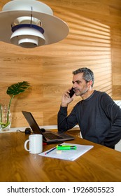 Businessman Talking On The Phone And Working On His Laptop In His Living Room