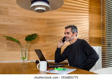 Businessman Talking On The Phone And Working On His Laptop In His Living Room