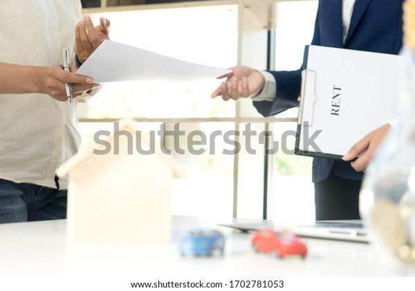 Businessman talks to the client with\
the contract paper about rent house or car in the white\
office.