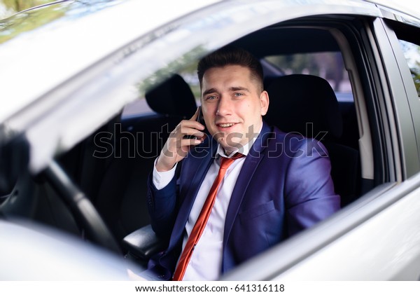 A businessman\
talks on the phone in the car