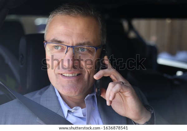 Businessman talks on the\
phone in a vehicle