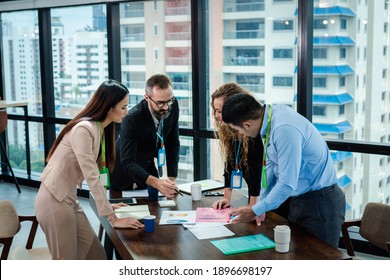 Geschäftsmann und Team sprechen und informieren über den Geschäftsplan und verwenden den Analysebericht im Sitzungssaal. Sie alle stehen davor, sich das Dokument anzusehen.