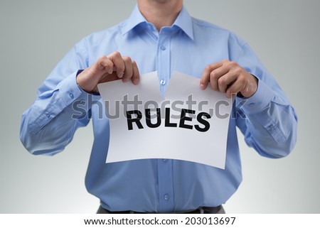 Businessman tearing up the rules or rulebook concept for innovation, creativity or mischief