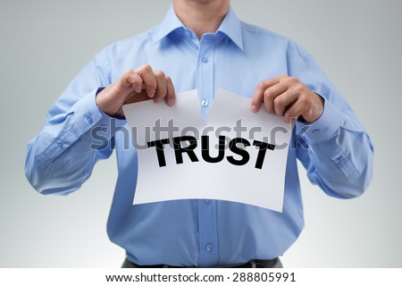 Businessman tearing up sign saying trust concept for infidelity, dishonesty and cheating